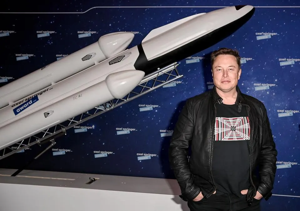 Elon Musk with model rocket behind him